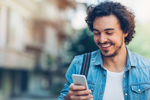 A man looking at the phone and smiling.