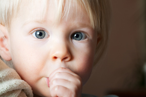 Little blonde boy sucking on his thumb.